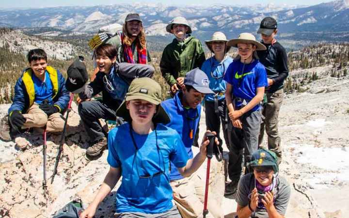 a group of students pose for a photo atop a rocky landscape